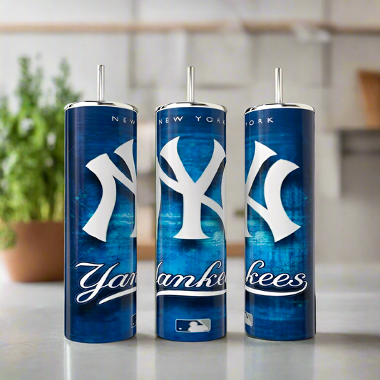 Three tall blue Kreative Kreationz New York Yankees 20oz tumblers with metal straws sit on a kitchen counter, each showing the team logo and name. A blurred plant is in the background.