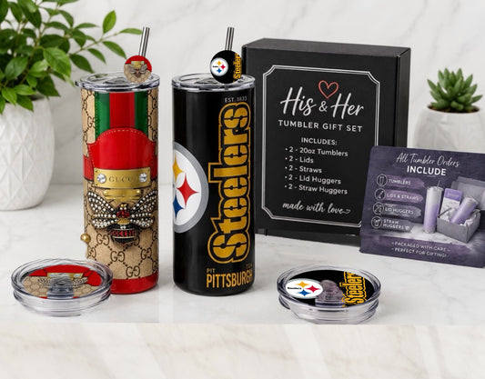 A Steelers themed tumbler gift set displayed on a white marble surface. The set includes a black 20oz tumbler with Steelers branding, a beige and green patterned tumbler, a black gift box labeled 'His & Her Tumbler Gift Set', a 'All Tumbler Codes Include' card, and two small clear-lidded accessories.