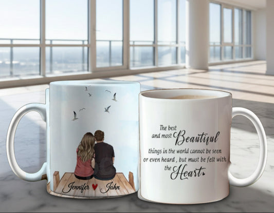 Two Personalized Couples Ceramic Mugs against a pink and red floral background: one depicts a couple on a dock with birds, while the other showcases a romantic heart-themed quote. These mugs offer customizable options to capture your unique love story.