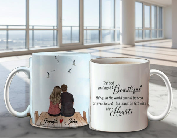 Two Personalized Couples Ceramic Mugs against a pink and red floral background: one depicts a couple on a dock with birds, while the other showcases a romantic heart-themed quote. These mugs offer customizable options to capture your unique love story.